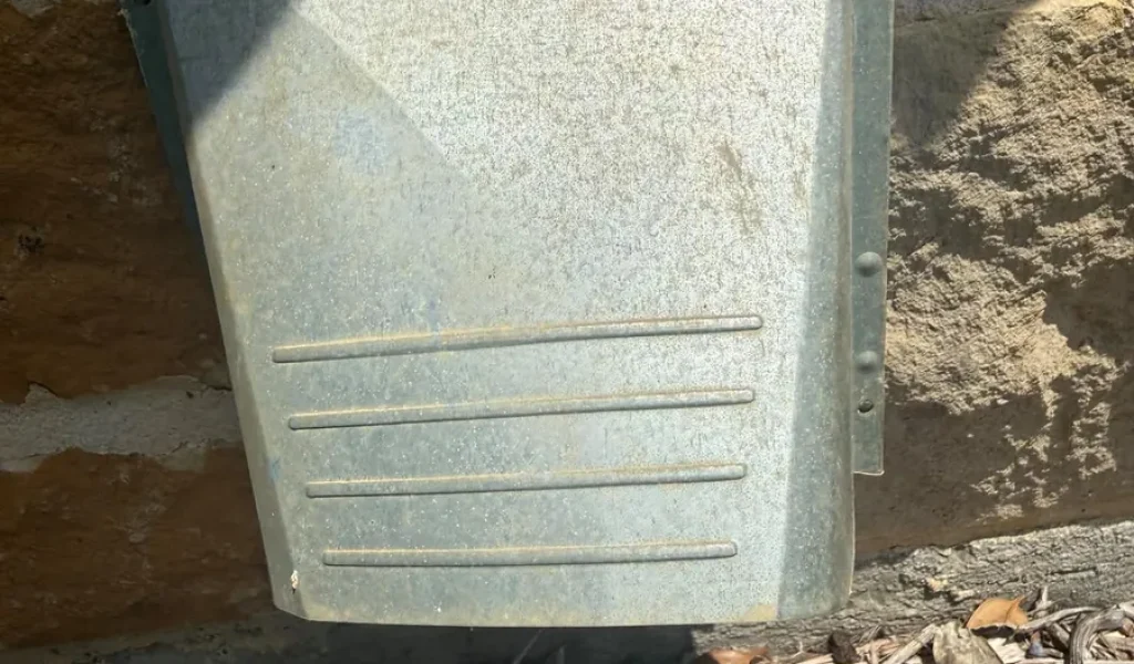 Galvanized exterior dryer vent hood installed on a stone wall