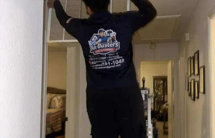 Air Busters technician servicing a ceiling supply vent in a DFW home