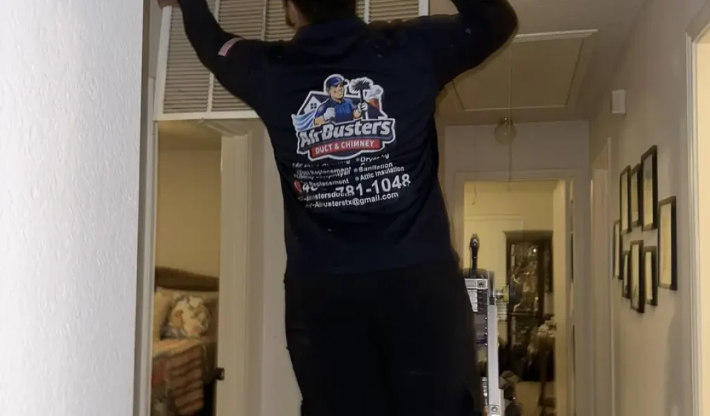 Air Busters technician servicing a ceiling supply vent in a DFW home